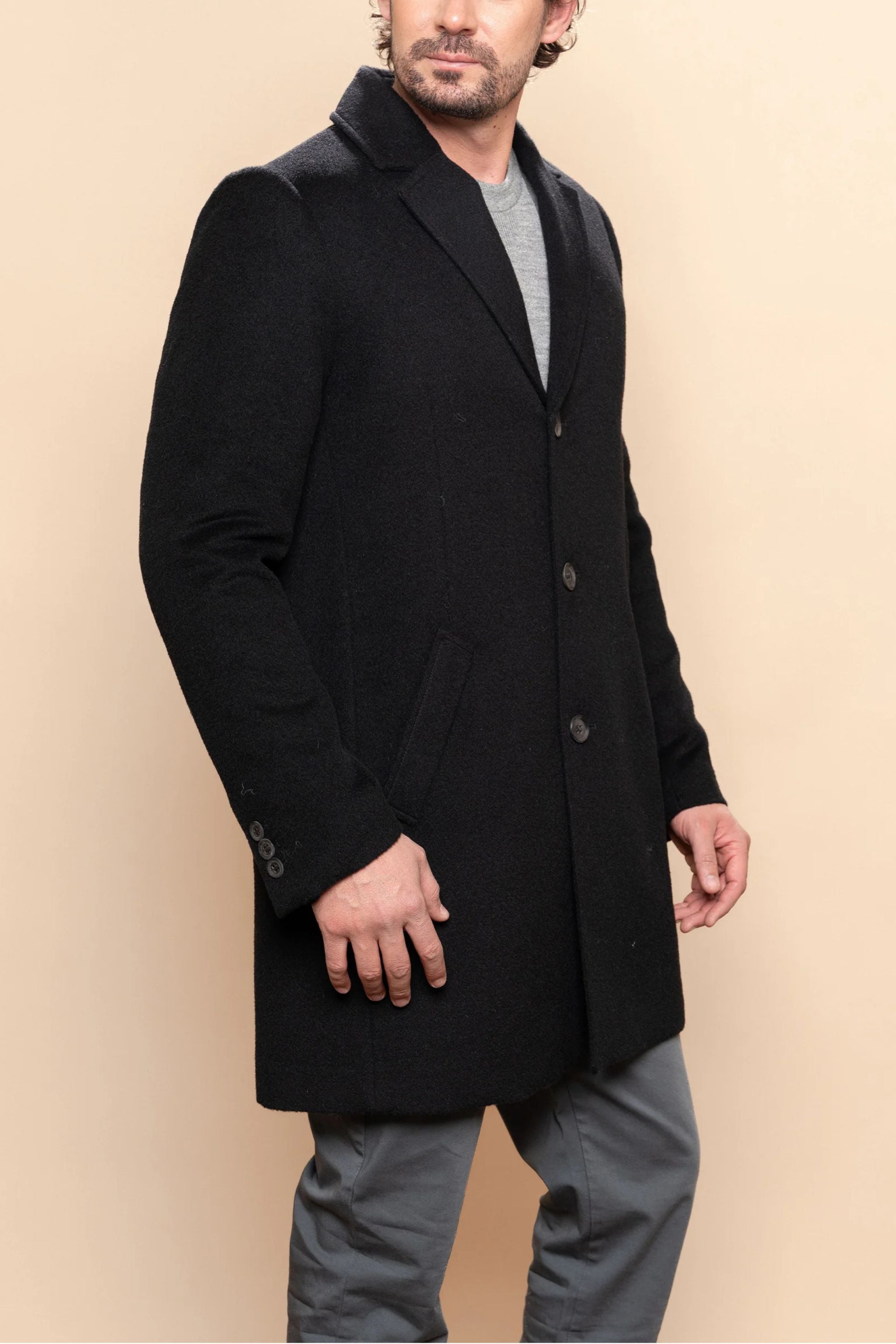 Man wearing a black coat on a beige background