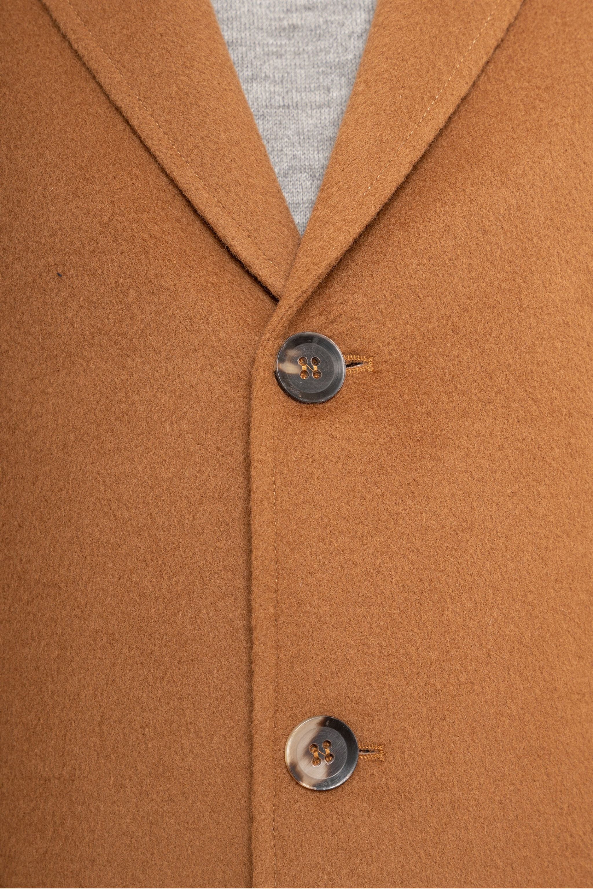 Close-up of a brown coat with two buttons on a gray background