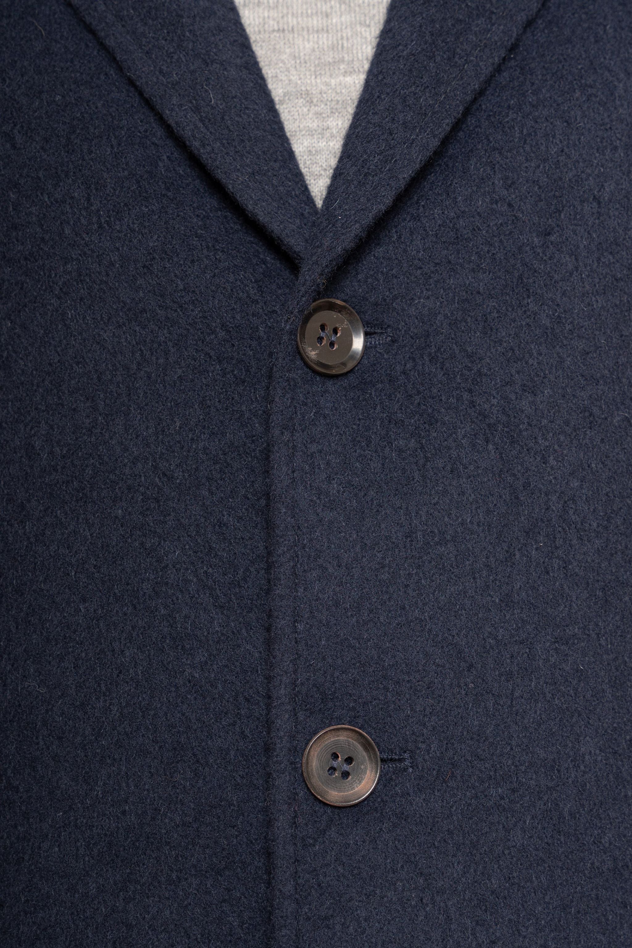 Navy blue coat with two buttons on a plain background