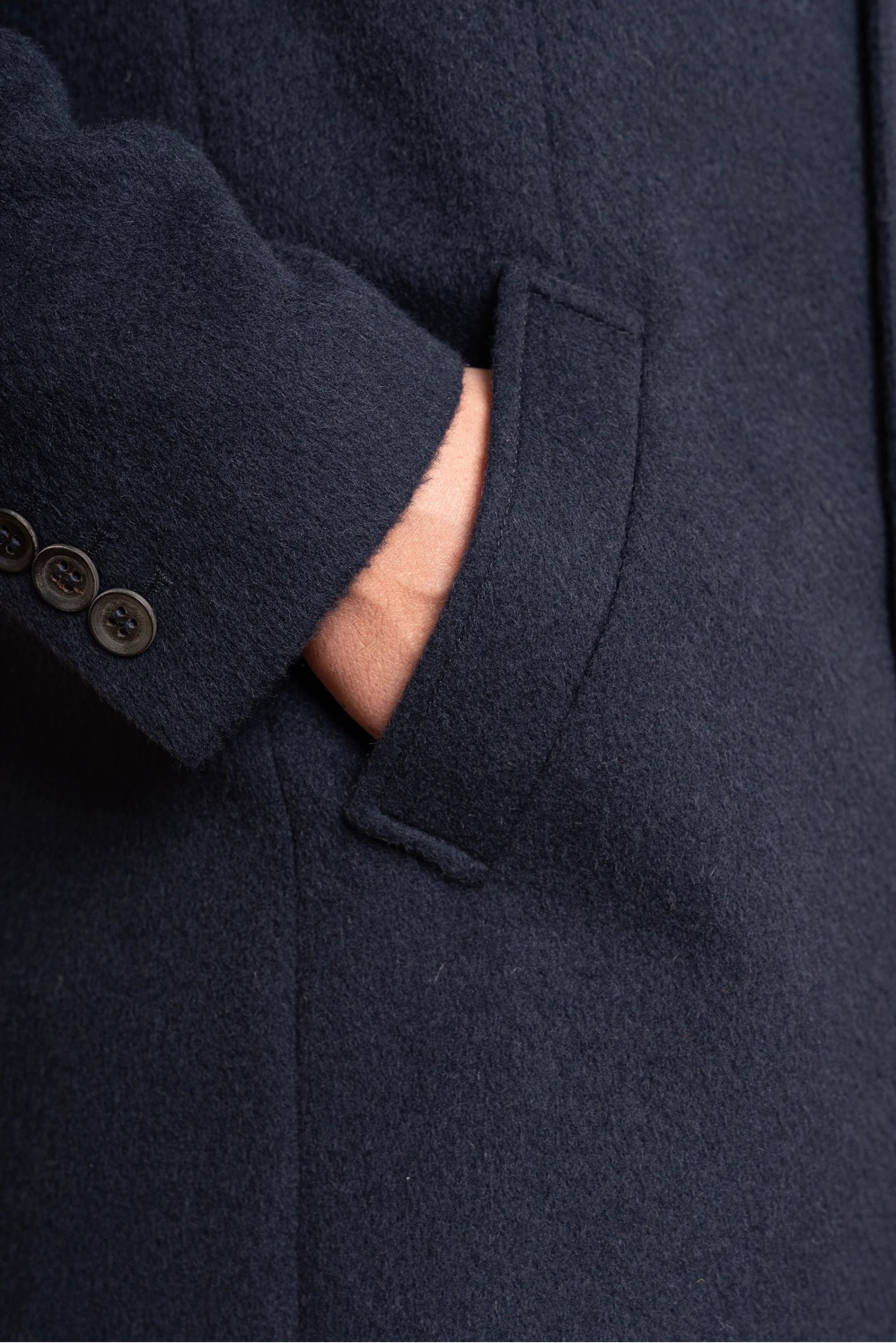 Navy blue coat with button details on a plain background