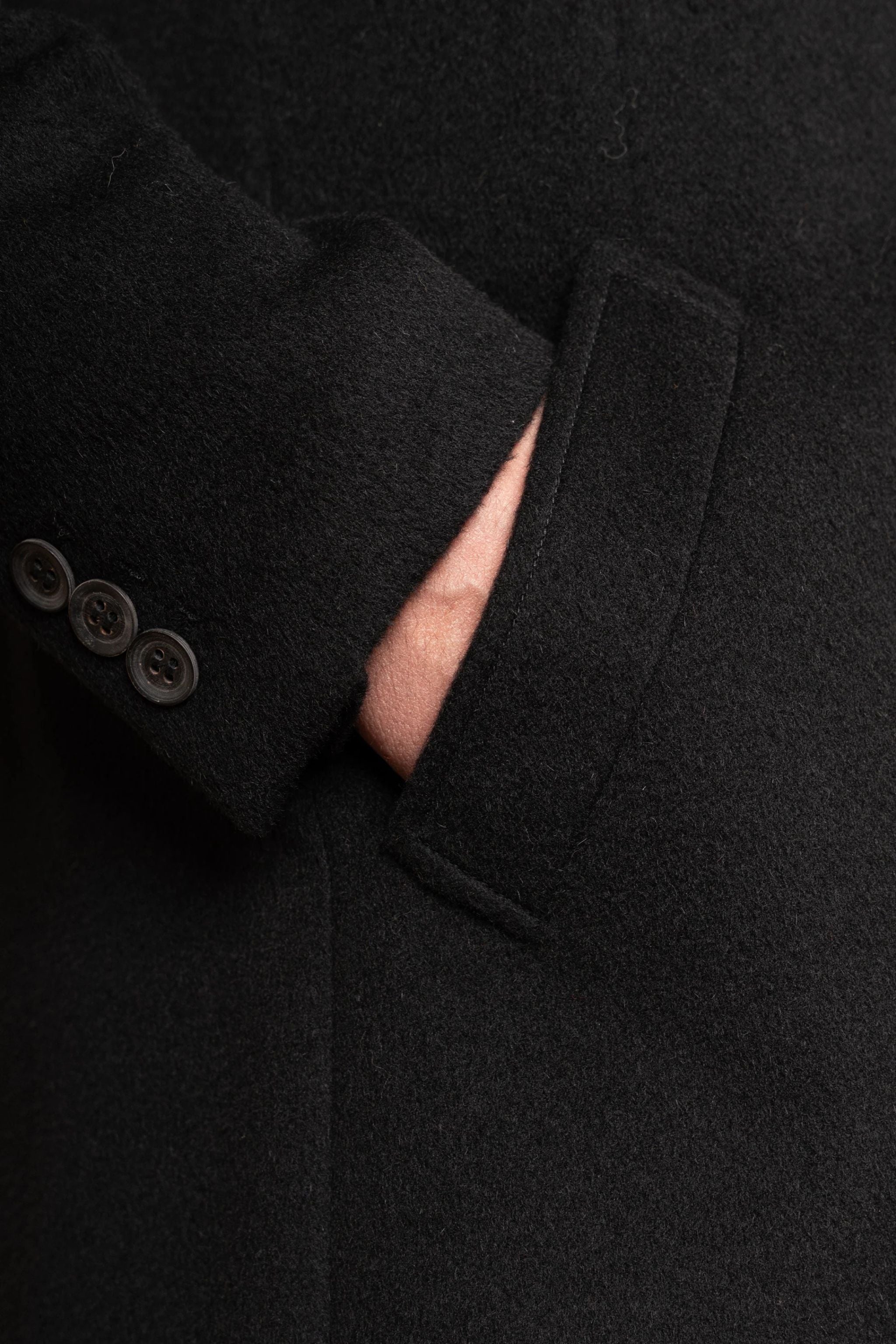 Close-up of a dark coat with buttons and a hood.